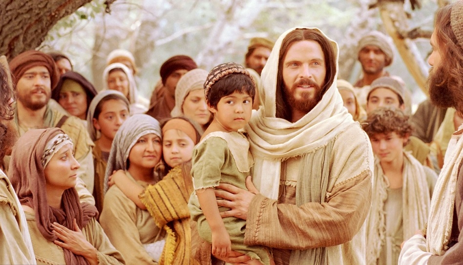 Jesus hält einen kleinen Jungen auf dem Arm.