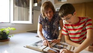 Eine Mutter und ihr Sohn schauen sich alte Fotos an, die in einem Fotoalbum eingeklebt wurden.