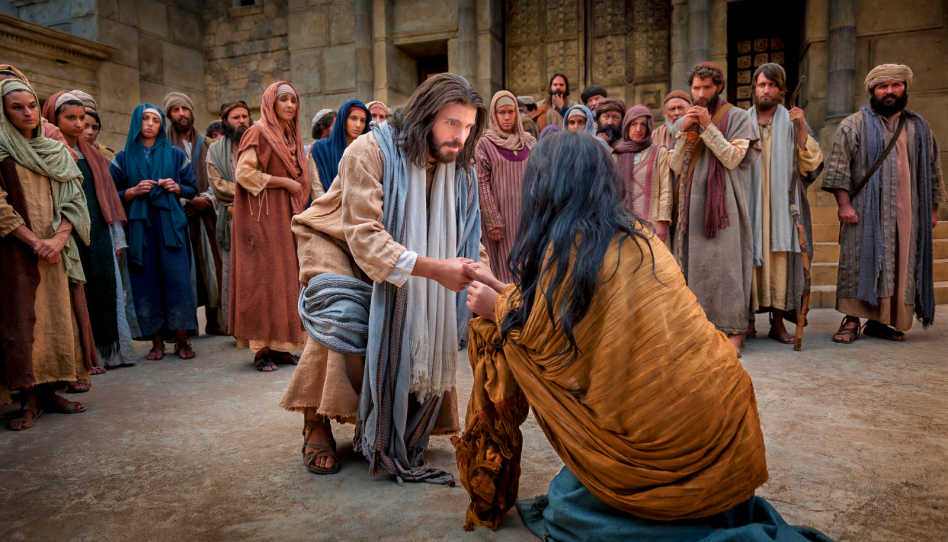 Jesus Christus beugt sich zu einer Frau runter und hält ihre Hand.