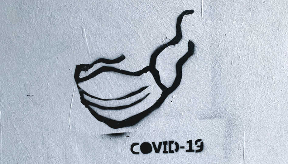 Zu sehen ist ein mit einer Sprühdose gemalte Maske und ein Covid-19-Schriftzug.