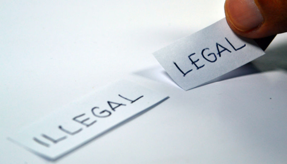 Auf diesem Bild sind zwei Zettel zu sehen. Einer mit der Aufschrift "illegal", der andere mit der Aufschrift "legal".
