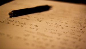Zu sehen ist ein Stift, liegend auf einem Zettel mit Mathematikaufgaben.
