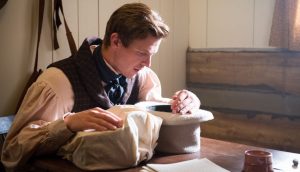 Zu sehen ist die Szene eines Films, in welcher Joseph Smith beim Übersetzen der goldenen Platten in einen Hut schaut. Darin hatte er einen Seherstein platziert.