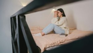 Eine Frau sitzt auf dem Bett und betet.