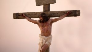 Jesus Christus hängt, mit einer Dornenkrone, am Kreuz und schaut zur Seite. Blut läuft von verschiedenen Wunden über seinen Körper.