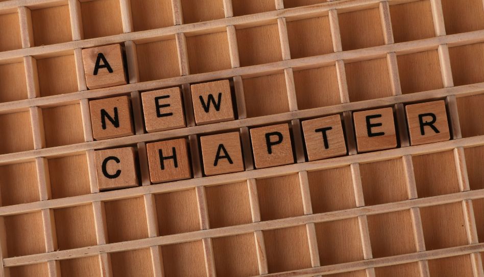 Viele kleine Holzkästchen. In einigen befinden sich Hollzwürfel auf denen Buchstaben stehen. Dadurch liest man die Worte "A NEW CHAPTER".