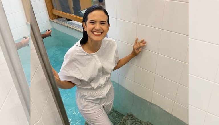 Eine junge Frau steigt aus einem Taufbecken und strahlt voller Freude