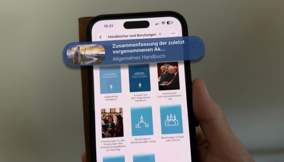 Ein Handy mit geöffneter App der Kirche Jesu Christi und einer Hervorhebung des Punktes “Allgemeines Handbuch“.